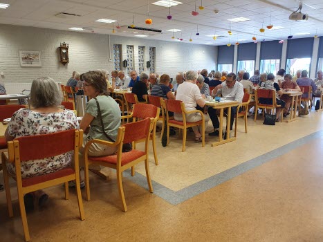 fullsatt samlingssal, många personer vid långbord