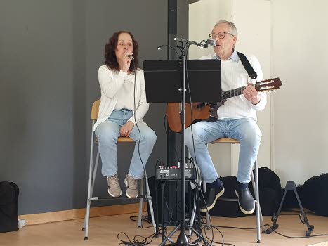 En man och en kvinna på scen. Mannen spelar gitarr och båda sjunger