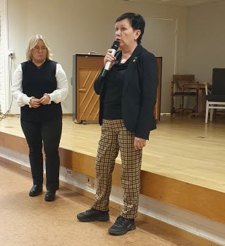 Två kvinnor som håller föredrag, en av dem talar med en handmikrofon medan den andra står vänd mot henne