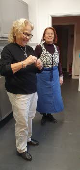 Två glada kvinnor i köket inför månadsmötet