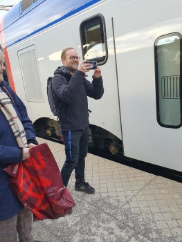 Man som fotograferar med sin mobil. Tåg i bakgrunden