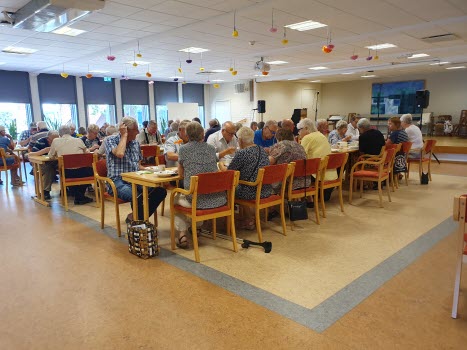 fullsatt samlingssal, många personer vid långbord