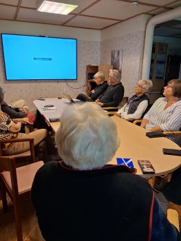 Seniorer runt konferensbord, deltar i ITkafé 