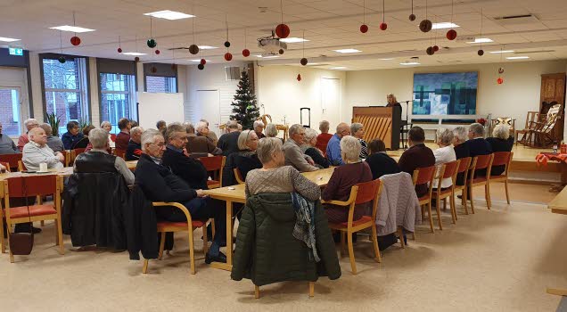 Seniorer vid tre långbord lyssnar till julmusik