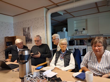 Seniorer runt konferensbord, deltar i ITkafé 