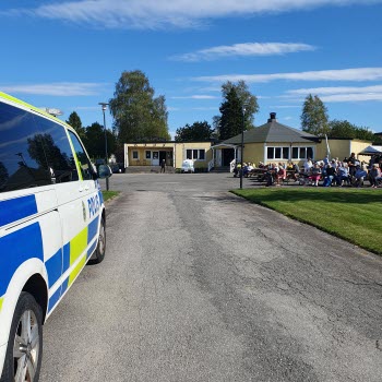 Folkets parks gula hus med utställningsområde framför. I förgrunden en polisbil.