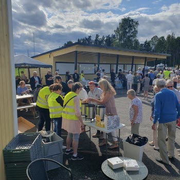 Kaffe servers utomhus från ett bord. Många pensionärer på utställningsområdet.
