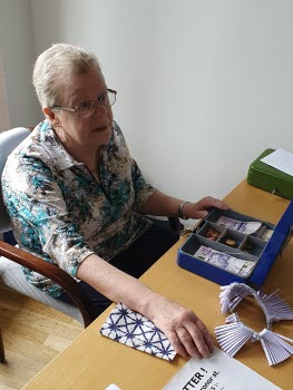 Dam sitter vid ett bord med kassalåda och lotteriring