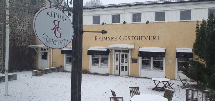Rejmyre gästgifveri, gul byggnas med namnet på väggen. Lätt pudersnö på marken