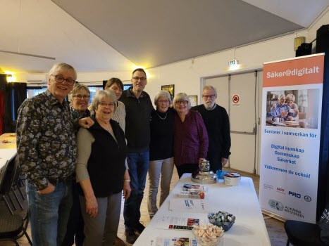 8 personer står vid ett utställarbord 